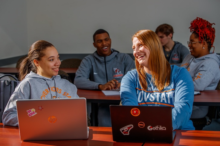 GovState students talking and typing on laptops